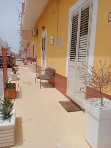 ein Gebäude mit Stühlen und Topfpflanzen auf dem Bürgersteig in der Unterkunft Victoria apartments in Lampedusa