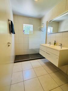 Blue Bay的住宿－# Blue Bay Beach - Ocean View Apartments #，带淋浴、盥洗盆和镜子的浴室
