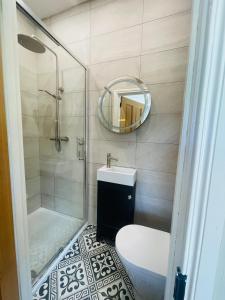 een badkamer met een douche, een wastafel en een spiegel bij Grey Heron Townhouse in Newcastle