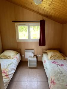 two beds in a small room with a window at Les Chalets du Piou in Bussières