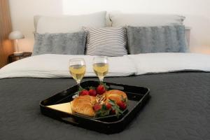 a tray of food and two glasses of wine on a bed at Apartman Agata,Osijek, self check-in in Osijek