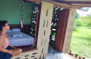 a woman is sitting in a room with a bed at Eco Hostel Lunar in Soure