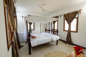 1 dormitorio con 1 cama con dosel en Mangapwani Beach villa en Fujoni