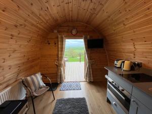a cabin with a kitchen and a door to a yard at The Pod Patch - Bryn Pod in Bishops Castle