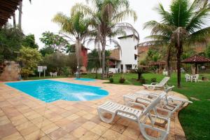 a swimming pool with two lounge chairs and a house at Hotel Fazenda Palmeiras in Rio Casca