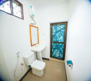 a bathroom with a toilet and a sink and a window at Mangapwani Beach villa in Fujoni