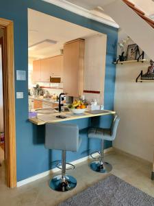 cocina con paredes azules, barra y 2 sillas en Seaview Penthouse Magnificó Ático Duplex con vistas al mar en Manilva