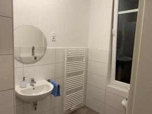 a white bathroom with a sink and a mirror at Appartementhaus EMDEN in Emden