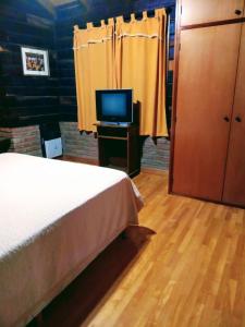 1 dormitorio con 1 cama y mesa con TV en Cabañas Legado Alemán en Villa General Belgrano