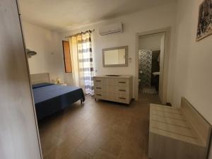 - une chambre avec un lit, une commode et un miroir dans l'établissement marco apartment, à Lampedusa