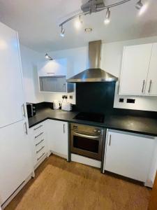 a kitchen with white cabinets and a black counter top at Exquisite City Centre Apartment - 2 Bed 2 Bath - Free Parking - Netflix Amazon Disney Enabled Smart TV in Birmingham