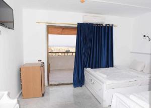 a room with a bed and a window with blue curtains at El Kasr Hotel in Marsa Matruh