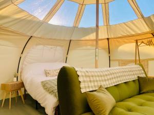 Una habitación con una cama y un sofá en una tienda de campaña en Luxury Stargazing Glamping - Seren Aur with Hot Tub, en Llanidloes