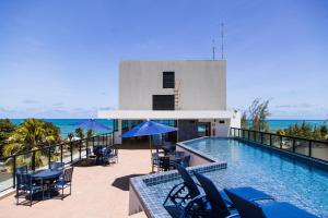 einen Pool mit Stühlen und Tischen auf einem Balkon in der Unterkunft Maracaipe Estrela Flat110 in Porto De Galinhas + 32 Fotos