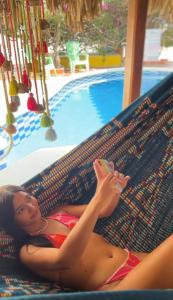 a woman laying on a hammock near a swimming pool at Hotel Casa Grande Riohacha Inn in R&iacute;ohacha