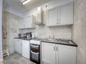 a kitchen with white cabinets and a sink at Apartment 4 - Large studio - Sea Front location - Rear views-Free Parking in Paignton