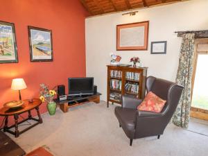 a living room with a chair and a television at The Shippon in Conwy