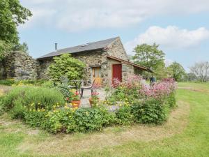 a stone cottage with flowers in front of it at The Shippon in Conwy