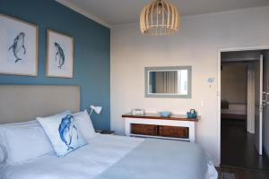 a bedroom with a bed with a blue accent wall at Penguin Paradise Apartment Simons Town in Simonʼs Town