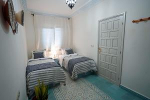 a bedroom with two beds and a door at Dar Badr in Tangier