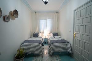 two beds in a room with a door and a window at Dar Badr in Tangier