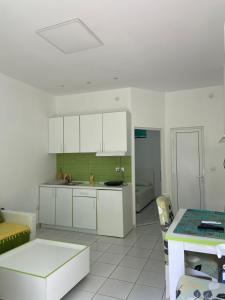cocina con armarios blancos, sofá y mesa en Apartmani Jovana, en Soko Banja