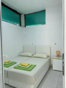 Un dormitorio con una cama blanca con toallas verdes. en Apartmani Jovana, en Soko Banja