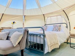 a bedroom in a tent with a bed and a chair at Luxury Stargazing Glamping - Seren Hardd with Hot Tub in Llanidloes +31 photos