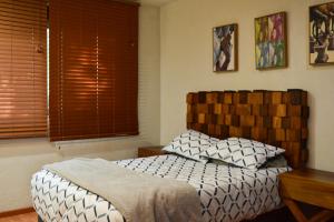 sypialnia z łóżkiem z drewnianym zagłówkiem i oknem w obiekcie Valentin House, very spacious and cozy. w mieście San Luis Potosí