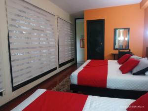 a bedroom with two beds with red pillows at Hotel La Herreria Colonial in Popayan