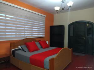 um quarto com uma cama com almofadas vermelhas e uma janela em Hotel La Herreria Colonial em Popayán