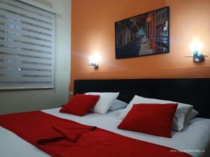 1 dormitorio con 1 cama con almohadas rojas y blancas en Hotel La Herreria Colonial, en Popayán