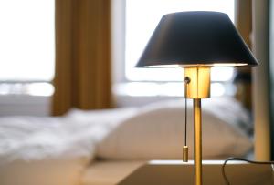 una lampada appoggiata su un tavolo davanti a un divano di Your homestay in a bibliophile mansion ad Anversa