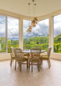 uma sala de jantar com mesa, cadeiras e janelas em Casa Campestre - Pet Friendly - Green Energy em Anapoima