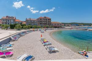 a beach with chaise lounges and chairs next to the water at Apartment Sidro in Postira +21 photos