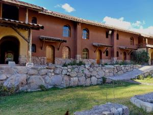 a large building with a stone wall in front of it at Willka Rumi in Urubamba