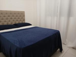 APARTAMENTO EM GARANHUNS PERTO De TUDO في غارانيونز: غرفة نوم مع سرير مع لحاف أزرق