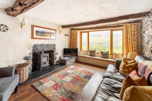 Una sala de estar con un sofá y una chimenea. en Longmire Yeat Cottage, en Troutbeck