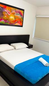 a bedroom with a bed with a painting on the wall at Hotel Casa Grande Riohacha Inn in R&iacute;ohacha