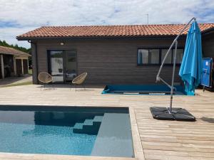 a pool with two chairs and an umbrella next to a house at ANGRESSE Villa Chris à 10 min d'HOSSEGOR in Angresse