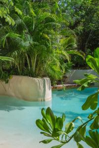 uma piscina com um monte de árvores e água azul em IIK Tulum Luxury Condo by Spot Rentals em Tulum