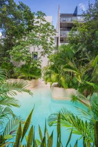 uma piscina com árvores e um edifício ao fundo em IIK Tulum Luxury Condo by Spot Rentals em Tulum