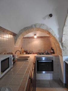 una cucina con piano cottura e arco in pietra di I trulli del Sole a Martina Franca