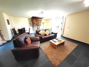 sala de estar con sofá de cuero y mesa de centro en Dolgun Uchaf Guesthouse and Cottages in Snowdonia, en Dolgellau