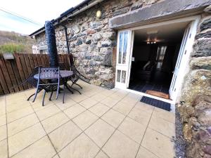a patio with a table and a chair on a porch at Dolgun Uchaf Guesthouse and Cottages in Snowdonia in Dolgellau