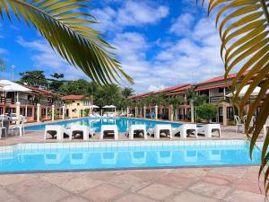 uma piscina com espreguiçadeiras em frente a um resort em A 200m da praia de Taperapuã Axé Moi 2 suítes, churrasqueira privativa, piscina, sauna portaria 24hrs e internet privativa 300MBPS em Porto Seguro