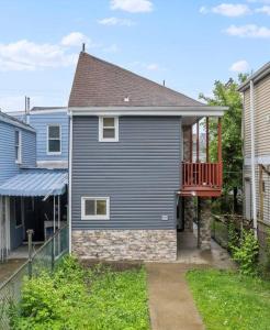 匹兹堡Bloomfield, Pittsburgh Large and Accessible 3 Bedroom Apr with Free Parking的院子里有一栋蓝色的房子，有一个红色的阳台