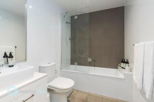 a white bathroom with a toilet and a shower at Redfern One Bedroom Apartment with Views in Sydney