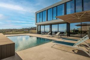 ein Haus mit Swimmingpool und Sonnenschirm in der Unterkunft Villa Elysian Oasis by Homie in Prazeres