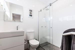 a white bathroom with a toilet and a shower at Bondi Beach Spacious Apartment in Sydney